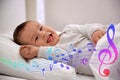 Flying music notes and cute baby lying in comfortable crib. Lullaby songs