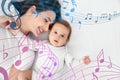 Flying music notes and mother with her cute baby lying on bed, top view. Lullaby songs