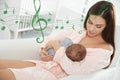 Flying music notes and woman with her baby at home. Lullaby songs