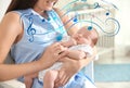 Flying music notes and woman with her newborn baby at home, closeup. Lullaby songs