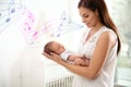 Flying music notes and woman and her newborn baby at home. Lullaby songs