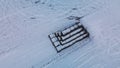 Flying over a snowy field. Straw bales are stacked. Traces of agricultural tillage are visible under the snow. Aerial photography