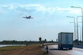 Flying Passenger Jet Plane on The Sky over The Container Truck Running on The Road