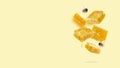 Flying pieces of honeycomb, drop of honey and bees on a yellow background. A conceptual composition of floating honeycombs.