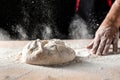 Flying pizza dough with flour scattering in a freeze motion of a cloud of flour midair on black. Cook hands kneading dough. copy Royalty Free Stock Photo