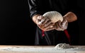 Flying pizza dough with flour scattering in a freeze motion of a cloud of flour midair on black. Cook hands kneading dough. copy Royalty Free Stock Photo