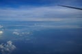 Flying on the plane seeing shades of tinted blue sky horizon background and sunrise light on white cloud with airplane wing Royalty Free Stock Photo