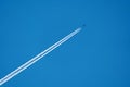 A flying plane with a white smoke trail on a blue sky background Royalty Free Stock Photo