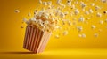 Flying popcorn bucket with popcorn exploding on yellow background Royalty Free Stock Photo