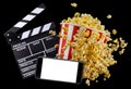 Flying popcorn, film clapper board and phone isolated on black background