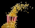 Flying popcorn from striped bucket isolated on black background