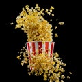 Flying popcorn from striped bucket isolated on black background