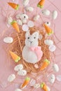 Flying quail eggs and White Rabbit in nest and sweet carrot on pink background. Easter minimal creative vertical composition with