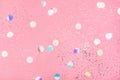 Flying silver holographic confetti on pastel pink background.