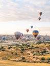 Flying in sky many bright colored beautiful balloons into air in Cappadocia in mountains early at sunrise, dawn. Filling