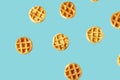 Flying small round waffles isolated on trendy blue background