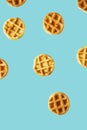 Flying small round waffles isolated on trendy blue background