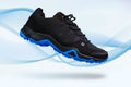 Flying touristic waterproof black and blue man shoe from side on wave white graphic background