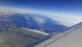 Flying and traveling abroad, bird eye view from airplane window on the jet wing on cloudy blue sky iceberg mountain aboard morning Royalty Free Stock Photo