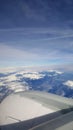 Flying and traveling abroad, bird eye view from airplane window on the jet wing on cloudy blue sky iceberg mountain aboard morning Royalty Free Stock Photo