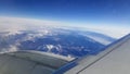 Flying and traveling abroad, bird eye view from airplane window on the jet wing on cloudy blue sky iceberg mountain aboard morning Royalty Free Stock Photo