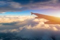 Flying and traveling, view from airplane window on the wing on sunset time. Aircraft wing under the earth and clouds. Flight in Royalty Free Stock Photo