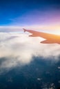 Flying and traveling, view from airplane window on the wing on sunset time. Aircraft wing under the earth and clouds. Flight in Royalty Free Stock Photo