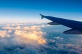 Flying and traveling, view from airplane window on the wing on sunset time. Aircraft wing under the earth and clouds. Flight in Royalty Free Stock Photo