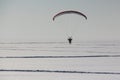 The flying-up person on a motorized paraglider against a snow Royalty Free Stock Photo
