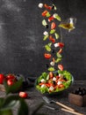 Flying vegetables are the ingredients of a Greek salad. On a dark background with props Royalty Free Stock Photo