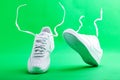 Flying white sneaker Nike on green background. Fashionable stylish leather sports casual shoes