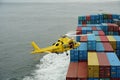 Flying yellow helicopter with Columbia River Bar pilot over containers. Royalty Free Stock Photo