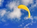 Flying yellow kite against blue cloudy sky