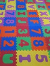 Foam colorful puzzle pieces. Children`s play rubber floor background. Texture of colored rubber pieces with numbers and letters Royalty Free Stock Photo