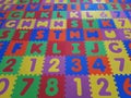 Foam colorful puzzle pieces. Children`s play rubber floor background. Texture of colored rubber pieces with numbers and letters Royalty Free Stock Photo