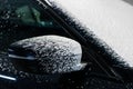 Foam drops dripping from a side mirror of a car.