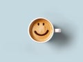 Foam form of smile face in cup of cappuccino coffee on blue pastel background. Generative AI. Royalty Free Stock Photo