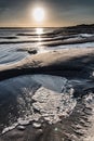 Foam in a puddle left by low tide at sunrise