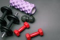 Foam rollers, dumbbells and yoga block on grey mat with massage roller. Set of fitness equipment on a gray background, front view Royalty Free Stock Photo