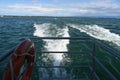 Foam trace in the water behind tourist, passenger catamaran sailing through the Lake Constance. Royalty Free Stock Photo