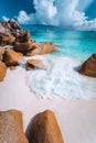 Foam wave between rocks on Grand Anse beach, La Digue, Seychelles. White clouds, crystal clear ocean and lonely luxury Royalty Free Stock Photo