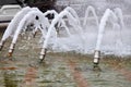 Foamy dense jets of water are frozen in their motion and burst out of the metal nozzles of the city fountain