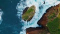 Foaming blue water breaking on stone cliff. Aerial stormy rough ocean crashing Royalty Free Stock Photo