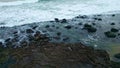 Foaming surf covering rocky coastline closeup. Sea waves splashing pebble beach Royalty Free Stock Photo