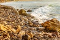 Foaming wave breaking at sunrise with rocky shoreline Royalty Free Stock Photo