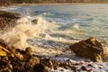 Foaming wave breaking at sunrise with rocky shoreline Royalty Free Stock Photo