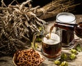 Foamy beer from bottle poured into mug standing with full mug beer with wheat and hops, basket of pretzels Royalty Free Stock Photo