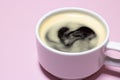 Foamy heart in a cup of black coffee on a pink background. Love concept