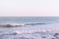 Foamy Rippled Sea Waves Rolling to Cliffy Shore Light Blue Water Pinks Purple Pastel Color Horizon. Beautiful Idyllic Seascape Royalty Free Stock Photo