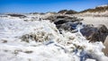 Foamy sea water splashing against rocks on the beach closeup Royalty Free Stock Photo